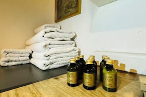 A stack of folded towels and several bottles of olive oil on a wooden surface. - Duplex with a Bosphorus view (Istanbul)