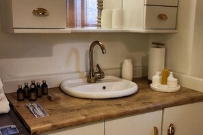 A bathroom with a wooden countertop, a white sink, and a mirror. There are toiletries on the counter and a towel rack to the left. - Duplex with a Bosphorus view (Istanbul)