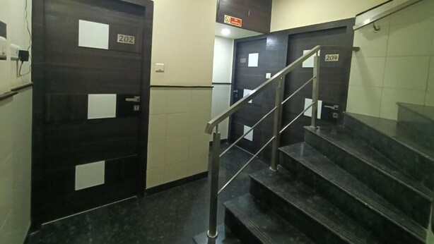 Una escalera con barandales de metal conduce a un rellano con puertas identificadas con los números 202 y 204.