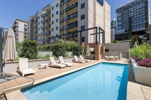A swimming pool with lounge chairs, a sun umbrella, and a view of multi-story buildings. - Mounts Bay Stay 2 Bedroom Apt - Kings Park - Free Parking (Perth)