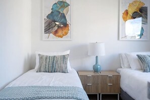 Un dormitorio con dos camas, una mesita de noche con lámpara y decoración en la pared.