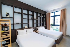 A hotel room with two beds, a wooden shelf unit, and a large window with curtains. - Lucky Phu Quoc Riverside Hotel Grand World (Phu Quoc Island)