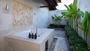 A modern bathroom with a freestanding bathtub, a wall-mounted sink, and a decorative relief sculpture. - Enchanting Canggu Villa (Bali)