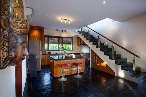 A modern kitchen with a central island, a staircase, and a large window. - Enchanting Canggu Villa (Bali)