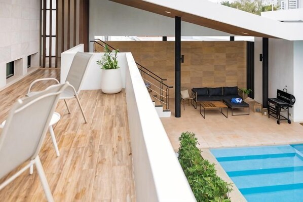 A modern outdoor area with a pool, seating, and a staircase.
