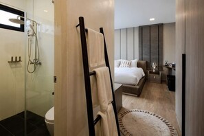 A modern bathroom with a glass shower enclosure, a towel rack, and a wooden floor.