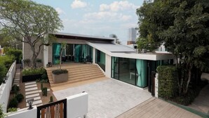 A modern house with a flat roof, large windows, and a wooden deck. - Prime Deluxe Villa No. V17 (Sattahip)