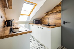 Une cuisine moderne dotée d’une lucarne, d’un four à micro-ondes, d’une bouilloire et d’un évier.
