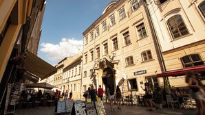 Une rue avec des terrasses, un bâtiment portant l’enseigne « 21LURINGH » et un ciel dégagé.