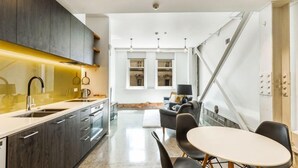 Una cocina moderna con armarios oscuros, una isla central y un comedor con una mesa redonda y sillas.