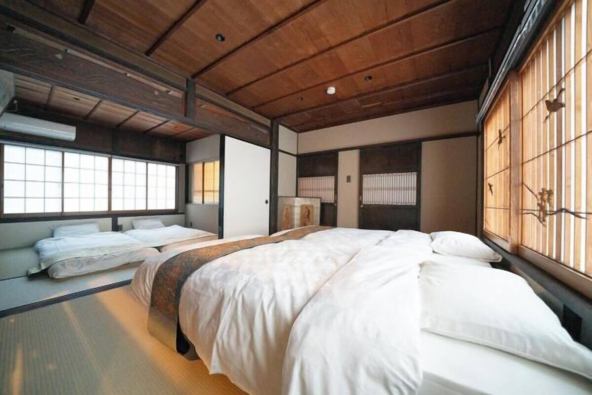 A traditional Japanese-style room with tatami flooring, a large bed with white bedding, and sliding doors with a decorative pattern.
