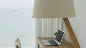 A laptop on a wooden desk with a lamp, near a window with curtains. - Beachfront 2 Bedroom Appartment with Glass wall by Villuxy (Da Nang)