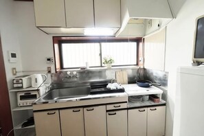 A compact kitchen with a sink, stove, and a window above the counter.