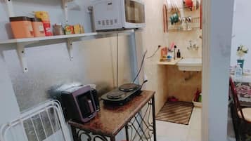 A compact kitchen with a microwave, kettle, and small countertop.