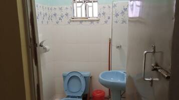 Un baño pequeño con dos inodoros, un lavamanos y una ducha.
