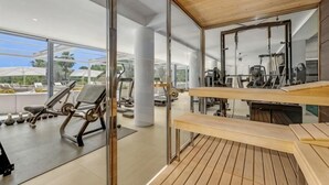 Ein modernes Fitnessstudio mit Trainingsgeräten, großen Fenstern und einem Holzboden.