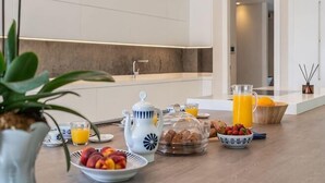 Cocina moderna con espacio para el desayuno, que incluye frutas, pastelería y una cafetera.