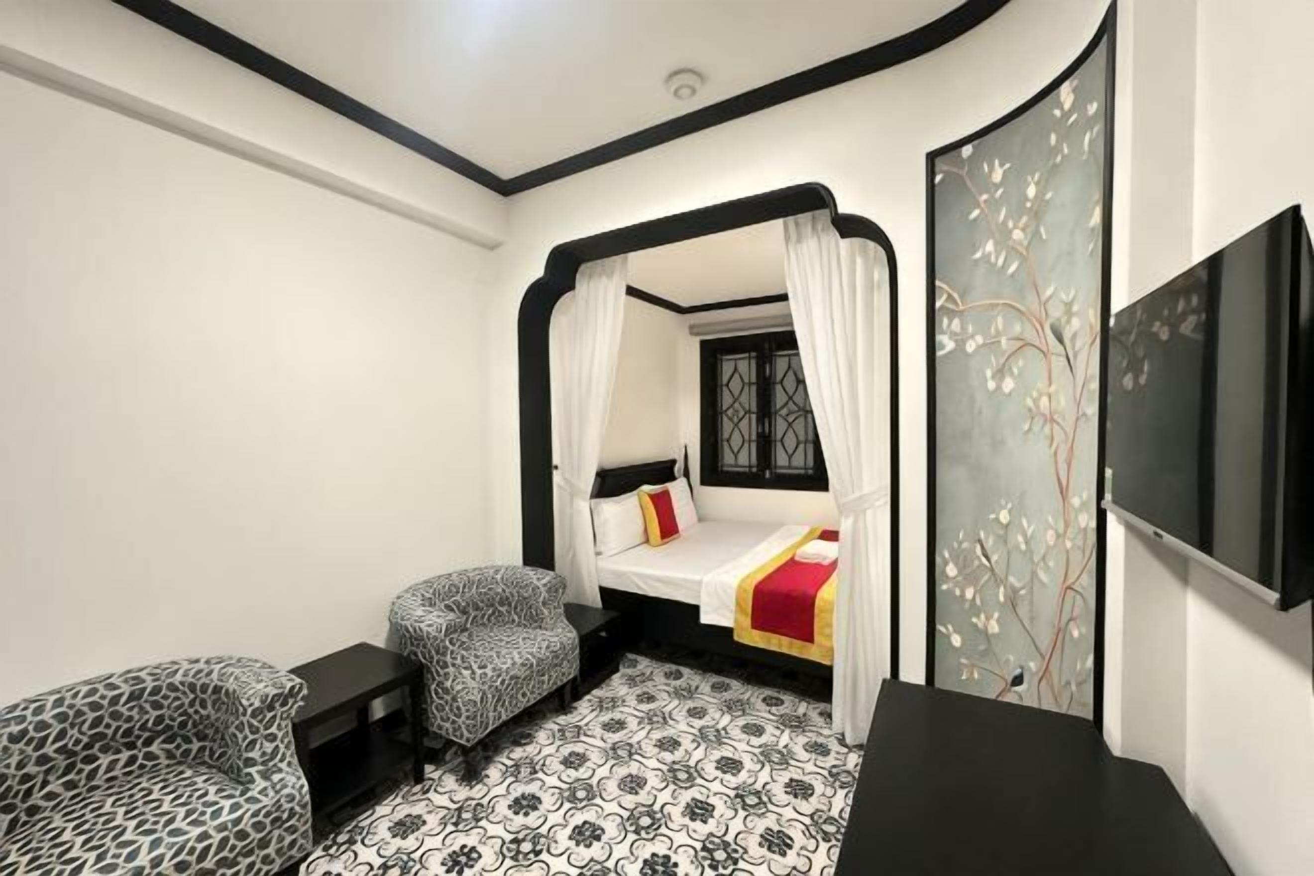 Ein Schlafzimmer mit Baldachinbett, Fernseher und gemustertem Boden.