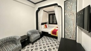 A bedroom with a bed, a chair, a TV, and a decorative wall. - Phu Gia 113 Nguyen Thi Thap (Ho Chi Minh City)