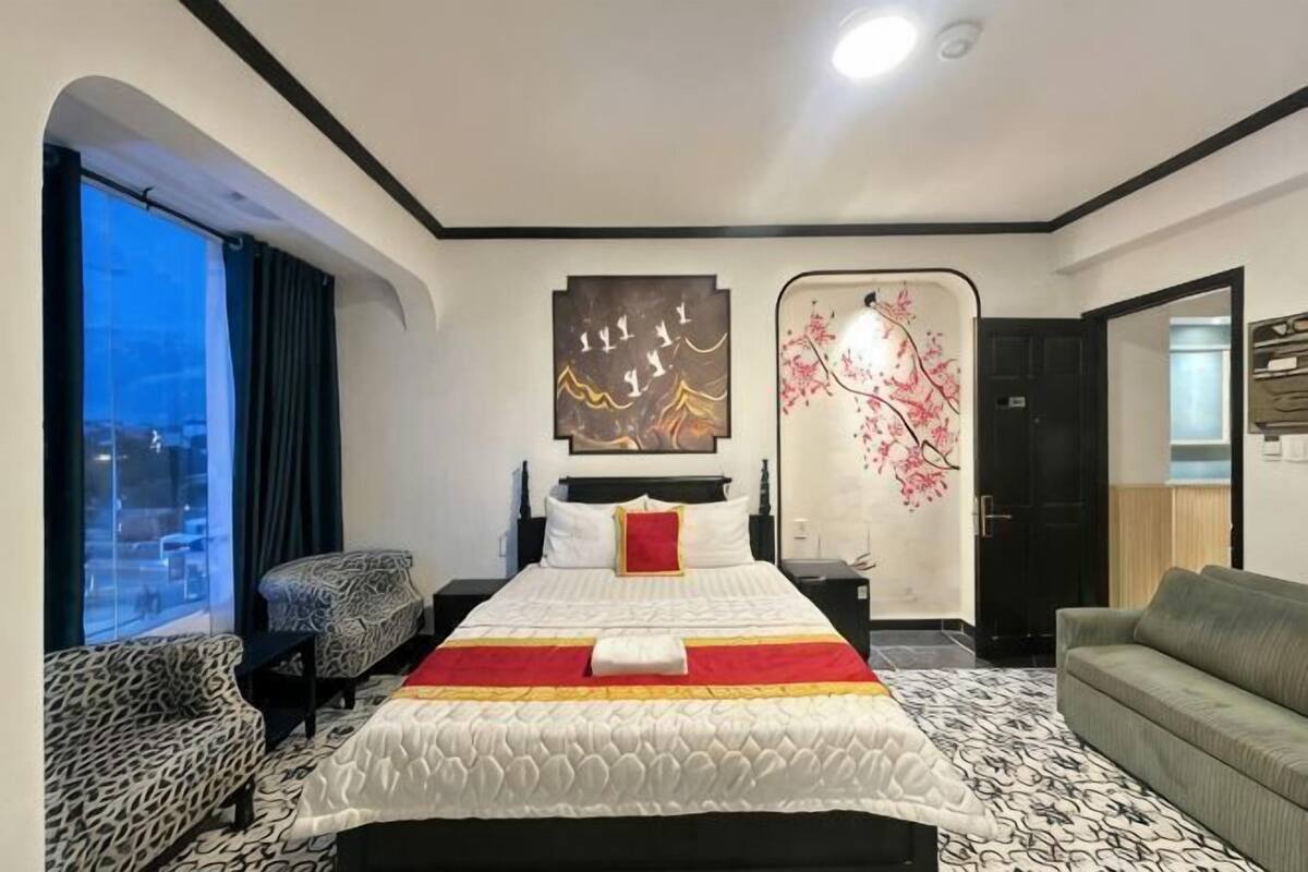 Ein Hotelzimmer mit einem großen Bett, einer Couch, einem Sessel und Blick auf die Stadt.