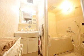 Casa de banho com banheira, lavatório, espelho e porta-toalhas.