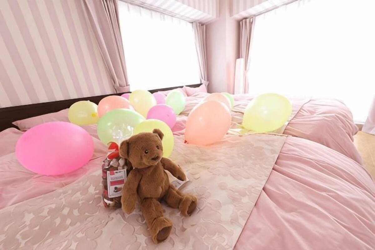 Een bed met een teddybeer en ballonnen.