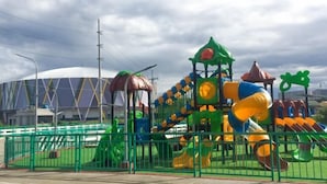 Un parque infantil con una estructura para escalar, toboganes y una zona delimitada.
