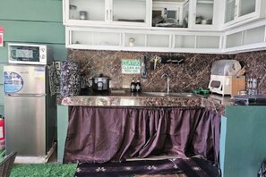 A kitchen with a microwave, a refrigerator, a sink, and a countertop with a sign that says 'CLAYGO CLEAN AS YOU GO.' - Natural Haven w/ Netflix,Videoke & Alfresco Dining (Dasmarinas)