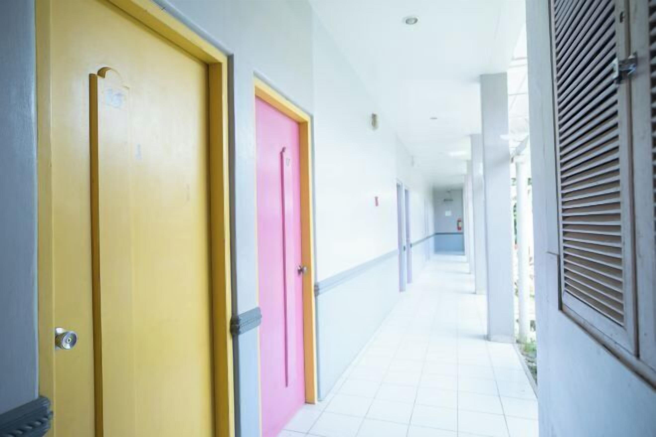 A corridor with doors, a tiled floor, and a window with blinds.