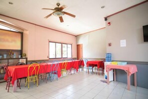 Une salle de conférence équipée de plusieurs tables et chaises, d’un ventilateur de plafond et d’une fenêtre.
