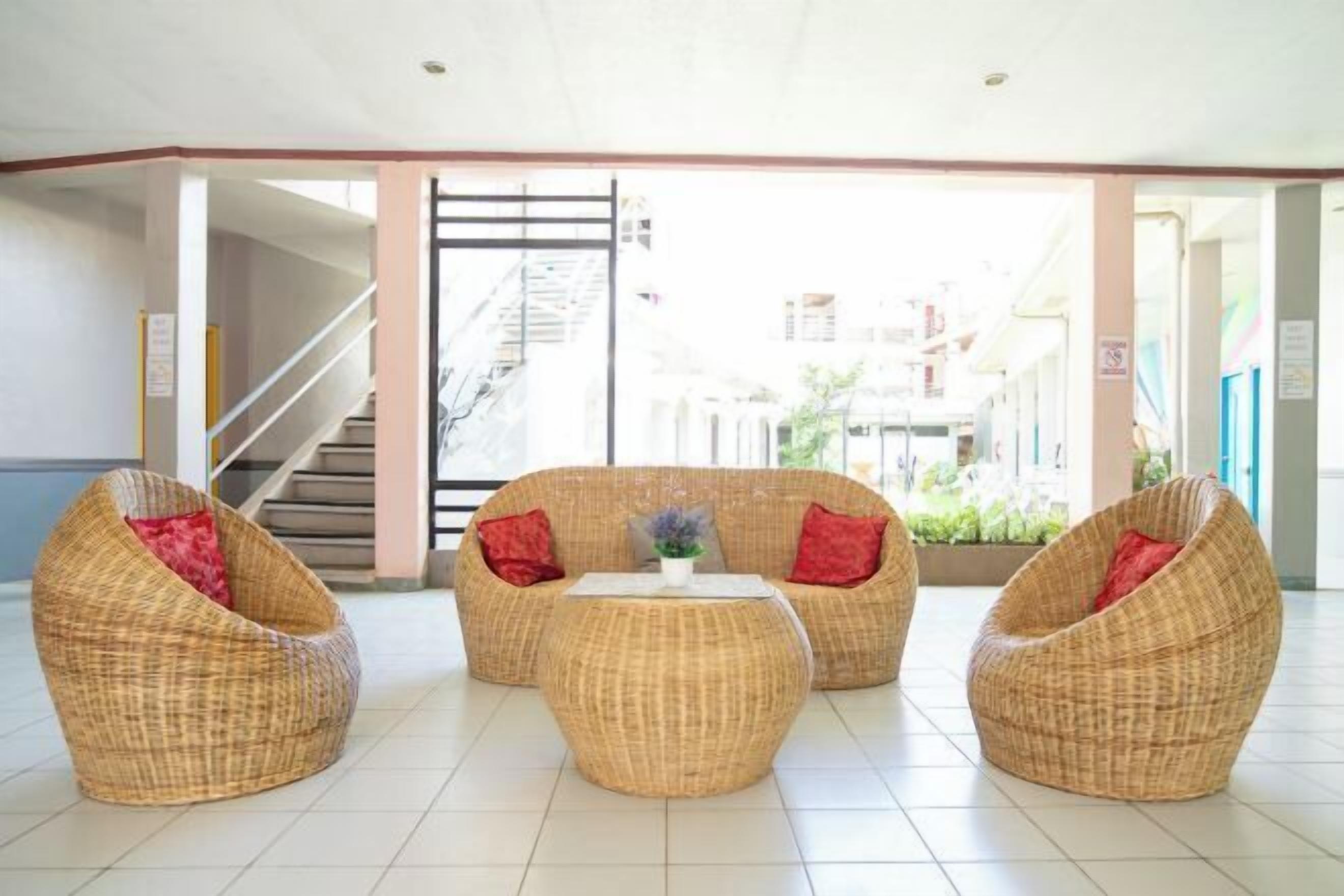 A lobby with wicker furniture, a staircase, and a view of buildings outside.