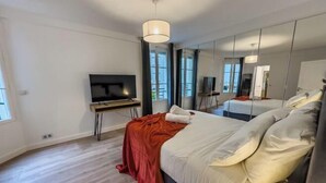 Une chambre d’hôtel moderne équipée d’un grand lit, d’une télévision, d’un bureau et d’un miroir.