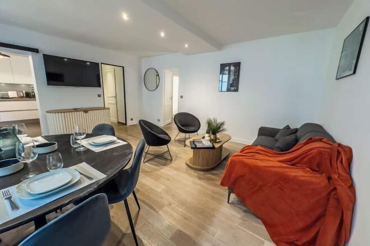 Ein modernes Wohnzimmer mit Essbereich, einer Couch und einem an der Wand befestigten Fernseher.