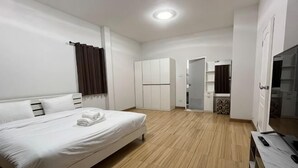 Une chambre à coucher comprenant un lit, une armoire, une télévision et une porte donnant accès à une salle de bain.