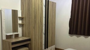 A bedroom with a bed, a wooden wardrobe, a mirror, and a small shelf. - Elly's Home. Convenience & Serenity (Chiang Mai)