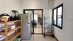 A narrow hallway with a kitchen area on the left, a refrigerator, and a window on the right. - Elly's Home. Convenience & Serenity (Chiang Mai)