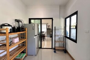 A narrow hallway with a kitchen area on the left, a refrigerator, and a window on the right. - Elly's Home. Convenience & Serenity (Chiang Mai)