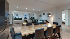 Ein modernes Wohnzimmer mit einem Holzespeisetisch, schwarzen Ledersesseln und einem Sofa.