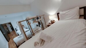 Ein Schlafzimmer mit Bett, Nachttisch, Lampe und Spiegel.
