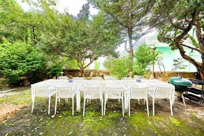 A dining area with a table and chairs, surrounded by trees and a stone wall. - JT_TEVA (USD) (Seoul)
