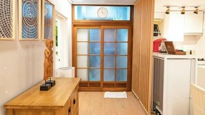 A narrow hallway with a wooden bench, a clock, and a sliding door with frosted glass panels. - JT_TEVA (USD) (Seoul)