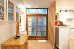 A narrow hallway with a wooden bench, a clock, and a sliding door with frosted glass panels. - JT_TEVA (USD) (Seoul)