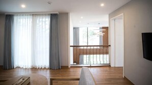 Un salon moderne avec un plancher en bois, un canapé, une table basse et un balcon doté d’une balustrade.