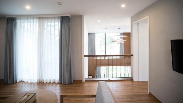 Un salon moderne avec un plancher en bois, un canapé, une table basse et un balcon doté d’une balustrade.