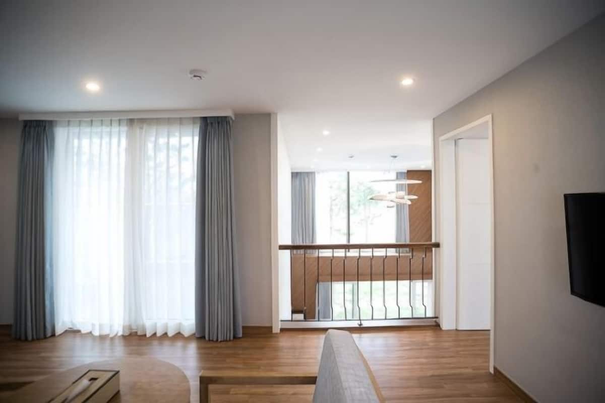 Ein modernes Wohnzimmer mit Holzboden, einer Couch, einem Couchtisch und einem Balkon mit Geländer.