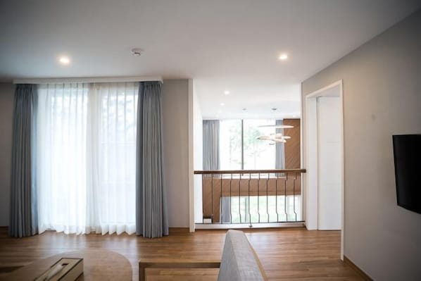 Una sala de estar moderna con suelo de madera, un sofá, una mesa de centro y un balcón con barandilla.