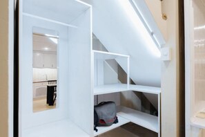 A compact room with built-in shelving, a visible kitchen area, and a staircase. - VietHOME - 22 Pho Hue - Duplex 602 (Hanoi)