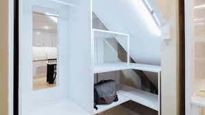 A compact room with built-in shelving and a visible kitchen area. - VietHOME - 22 Pho Hue - Duplex 602 (Hanoi)