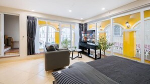 A modern hotel room with a bed, a sofa, a TV, and a small table. - VietHOME - 22 Pho Hue - Duplex 602 (Hanoi)