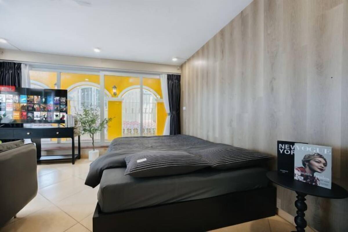 A modern hotel room with a bed, a small table, a desk with a computer, and a magazine on the table.